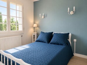 A bedroom with a bed, a window, a nightstand, and wall-mounted lights. - Domaine de la Barthe - Spacious Apartment in a Vineyard (Béziers)