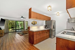 Eine moderne Küche mit Holzausstattung, einem Kühlschrank, einer Spüle und einem Deckenventilator.