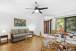 A living room with a sofa, a round table, and a ceiling fan. - Poipu Ground-Floor Gem | New A/C, Sleeps 6, Walk to Shopping & Dining (Koloa)