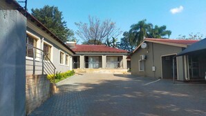 A building with a red-tiled roof, a paved courtyard, and a satellite dish on the side.