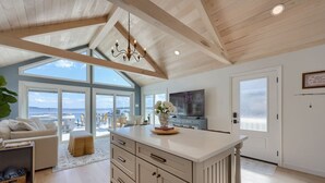 A spacious living area with a large window, a kitchen island, and a television.