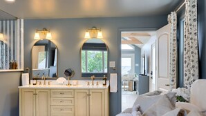 Une salle de bain avec un meuble-lavabo double, deux grands miroirs et une fenêtre.