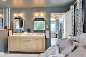 Une salle de bain avec un meuble-lavabo double, deux grands miroirs et une fenêtre.