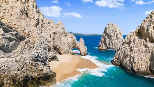 Un paysage côtier caractérisé par des falaises rocheuses, une plage de sable et des eaux turquoise.