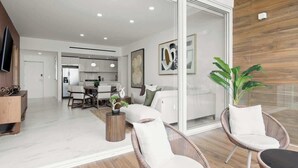 Un salon moderne avec des fauteuils en osier, un coin repas et une cuisine en arrière-plan.
