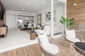 Ein modernes Wohnzimmer mit Korbstühlen, einem Essbereich und einer Küche im Hintergrund.