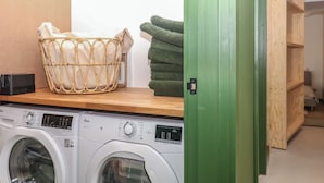 Un espace dédié à la lessive, comprenant un lave-linge, un panier à linge en osier et une pile de serviettes.