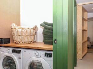 A laundry area with a washing machine, a wicker laundry basket, and a stack of towels.