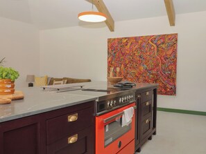 Una cocina moderna con una isla grande, un horno rojo y un cuadro abstracto colorido en la pared.