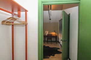 A hallway with a wooden coat rack, a desk with a lamp, and a dog lying on the floor.