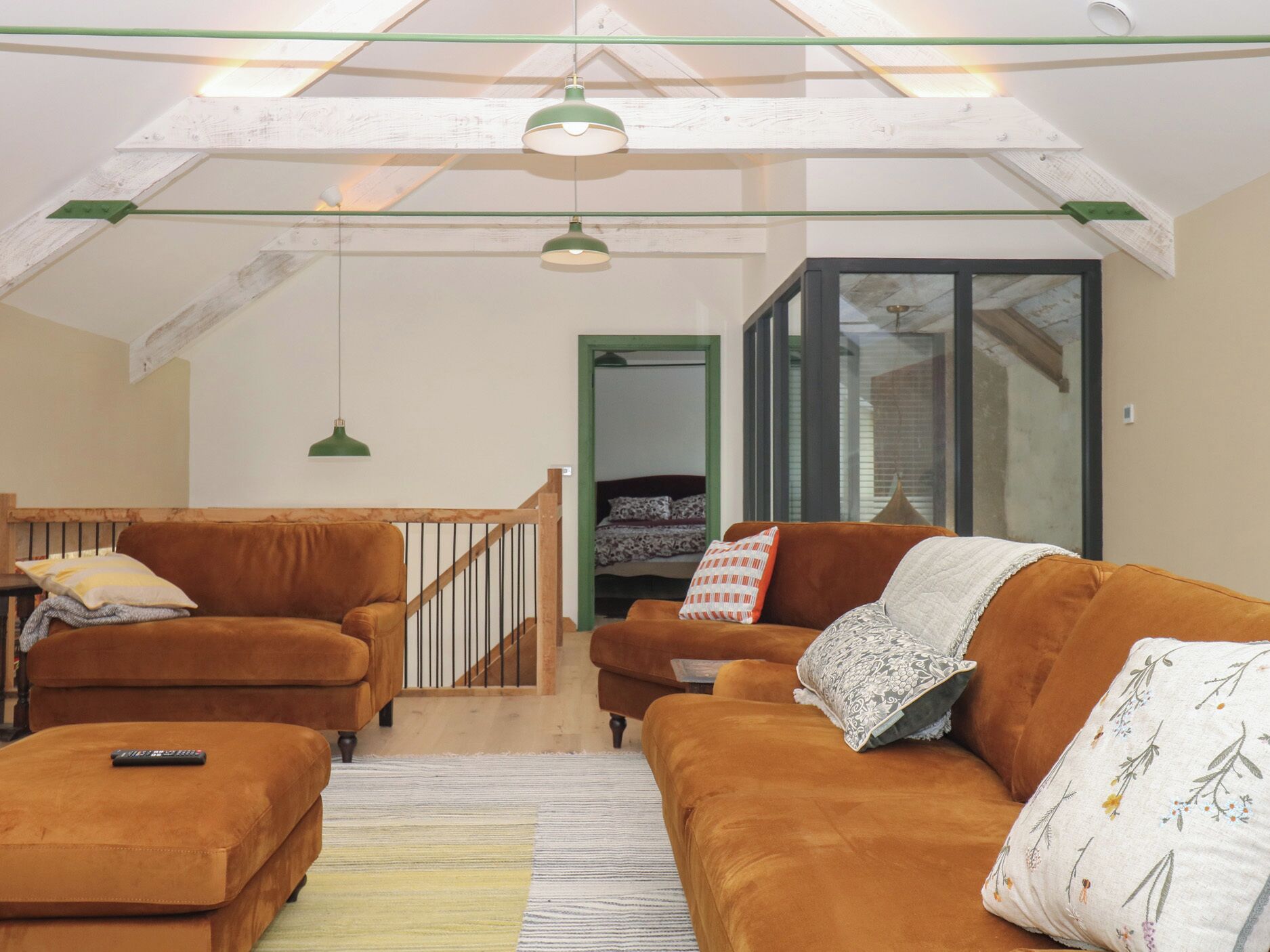 Un salón estilo loft con una escalera de madera, dos sofás, una mesa de centro y una lámpara colgante.