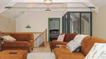 Un salón estilo loft con una escalera de madera, dos sofás, una mesa de centro y una lámpara colgante.