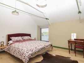 Un dormitorio con cama, escritorio, silla, ventana con persianas y alfombra de piel de vaca.
