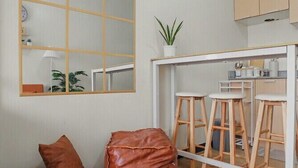 A modern kitchen with a white countertop, wooden stools, and a large mirror. - Serene Stay at Paseo Verde (Las Piñas)