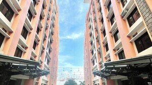 A building with a circular patterned floor, multiple balconies, and a clear sky. - Serene Stay at Paseo Verde (Las Piñas)