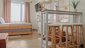 A bedroom with a bed, a desk with stools, a ceiling fan, and a window with curtains. - Serene Stay at Paseo Verde (Las Piñas)