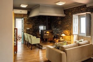 Ein gemütliches Wohnzimmer mit Kamin aus Stein, einer Couch und einem Essbereich mit Stühlen.