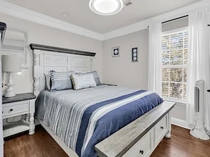 A bedroom with a bed, bedside tables, a bench, a window with curtains, and a ceiling light. - Ocean Views, 5 min walk to Beach, Waterpark, Arcade, Store ~ 5 bd/3; Sleeps 10 (Myrtle Beach)