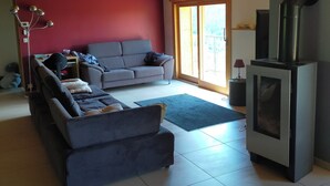 Un salon avec un canapé, une cheminée et une grande fenêtre.