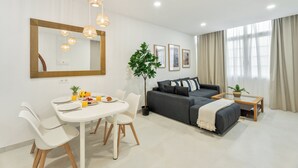 Una sala de estar moderna con comedor, un sofá gris, una mesa de centro y un espejo grande.