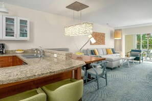 A modern kitchen with granite countertops, a dining area with a wooden table and chairs, a gray sofa with cushions, and a large window offering a view of the outdoors. - 2 bedroom, 2 bath Resort Villa in Beautiful Orlando, Florida with room for 8 (Orlando)