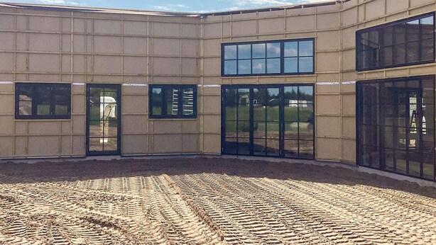 Een gebouw met een plat dak, grote ramen en een binnenplaats met een versierde vloer.