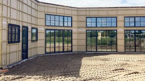 Een gebouw met een gebogen gevel, grote ramen en een zandachtige grond.