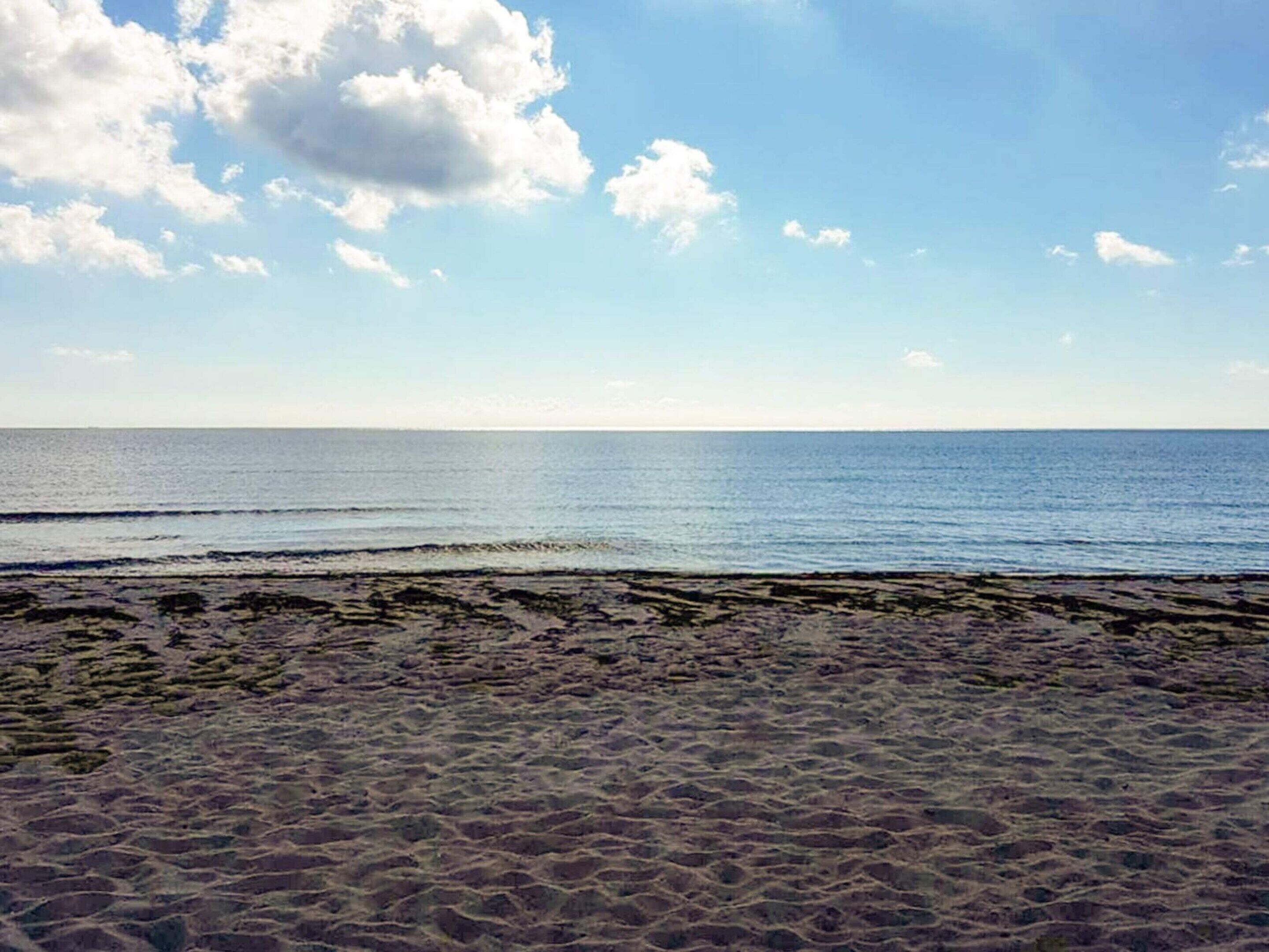 A beach with a clear sky and calm sea.