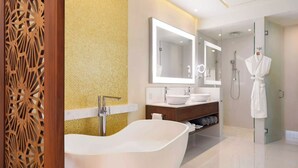 Ein modernes Badezimmer mit einer freistehenden Badewanne, einem großen Spiegel und einem an der Tür hängenden Bademantel.