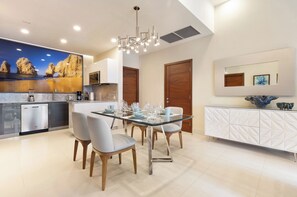 Une cuisine moderne avec un coin repas, comprenant une table en verre, des chaises et un four encastré.