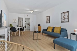Een moderne woonkamer met een bank, een salontafel en een eetgedeelte met stoelen.