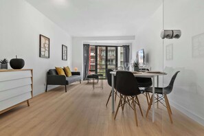 A modern living room with a dining area, a sofa, a coffee table, and a TV. - Casiola - Stylish 2BR Apartment in Knokke (Knokke-Heist)