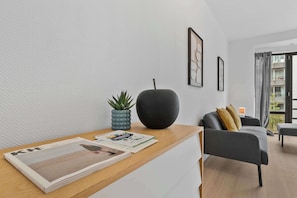 Ein modernes Wohnzimmer mit einem Holztisch, einer schwarzen Vase und einem grauen Sofa.