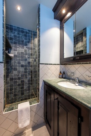 A bathroom with a glass-enclosed shower, a sink, and a mirror. - Fully renovated 5-bedroom apartment in Verbier (Verbier)