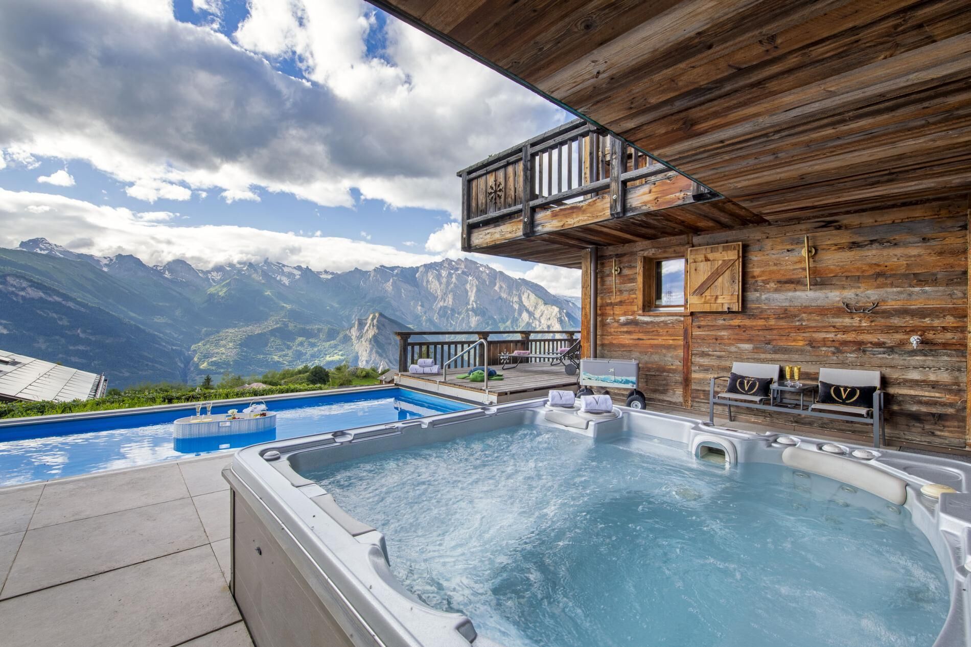 Une cabane en bois avec une piscine et un jacuzzi, offrant une vue sur une chaîne de montagnes.