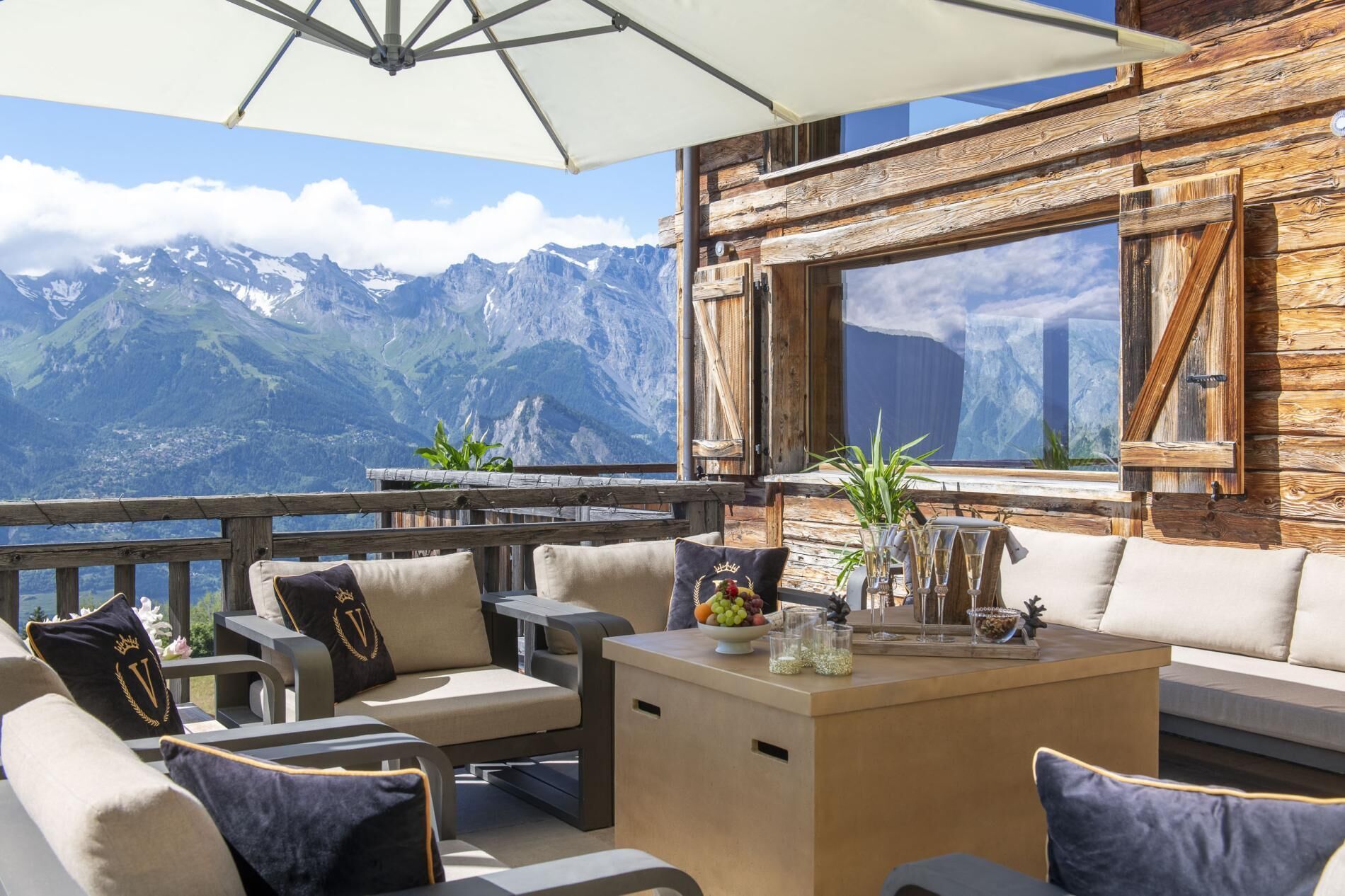 Une terrasse avec des sièges extérieurs, une vue sur les montagnes et un mur en bois.