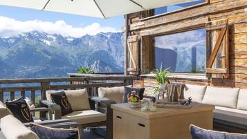 Une terrasse avec des sièges extérieurs, une vue sur les montagnes et un mur en bois.