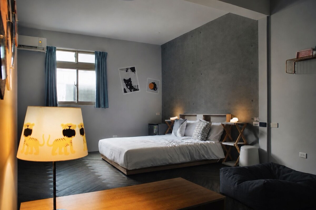 Ein modernes Schlafzimmer mit einem Bett, Nachttischen, einer Lampe und einer Couch.