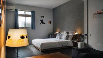 Un dormitorio moderno con una cama, mesitas de noche, una lámpara y un sofá.