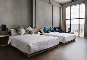 Ein modernes Hotelzimmer mit zwei Betten, einem Holzkopfstück und einem großen Fenster mit Vorhängen.