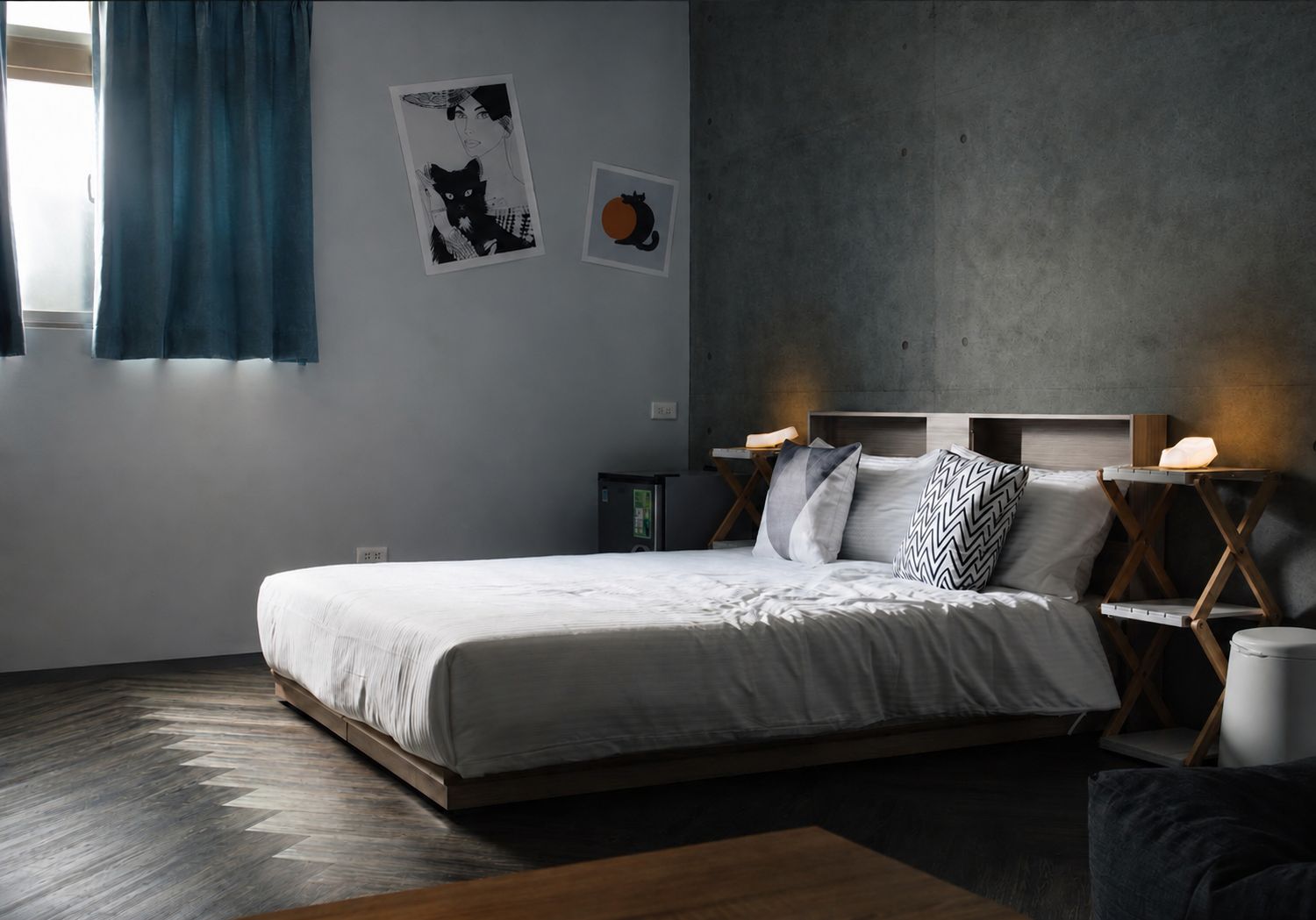 A modern bedroom with a large bed, a headboard with integrated reading lights, and artwork on the wall.