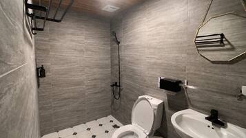 A modern bathroom with a shower, toilet, and sink.