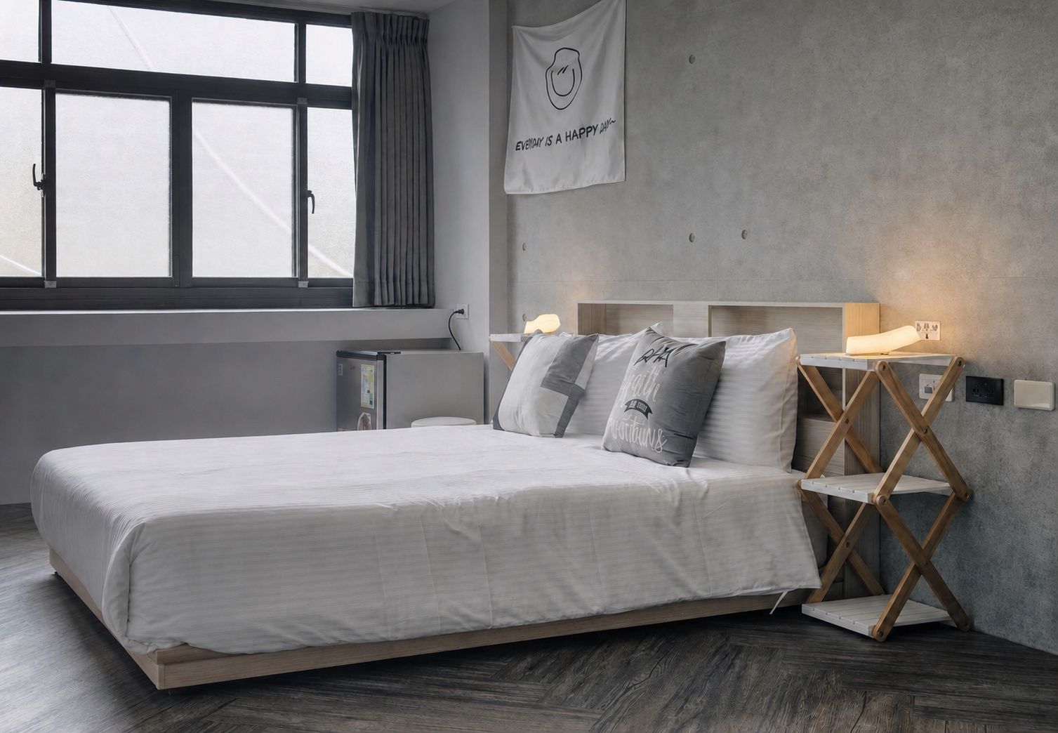 Een moderne slaapkamer met een groot bed, nachtlampjes en een wandlamp.