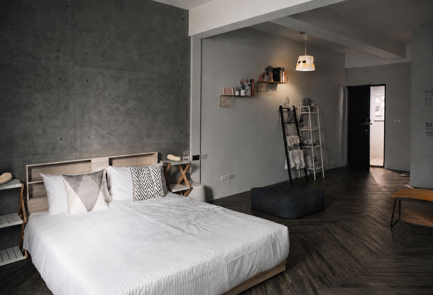A modern bedroom with a large bed, bedside tables, a wardrobe, a ladder, and a hanging light fixture.