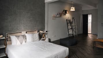 A modern bedroom with a large bed, bedside tables, a wardrobe, a ladder, and a hanging light fixture.