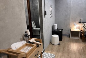 Ein modernes Badezimmer mit einer Holzbank, Toilette, Waschbecken und einem kleinen Nachttisch mit Lampe.