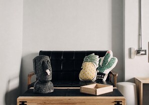 A black sofa with a wooden tray in front, a stone sculpture, and two decorative pillows.