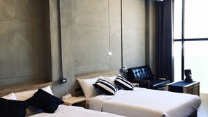 A hotel room with two beds, a chair, a small table, and a window with curtains. - Realm Loft (Kaohsiung)