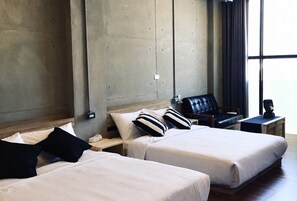 A hotel room with two beds, a chair, a small table, and a window with curtains. - Realm Loft (Kaohsiung)