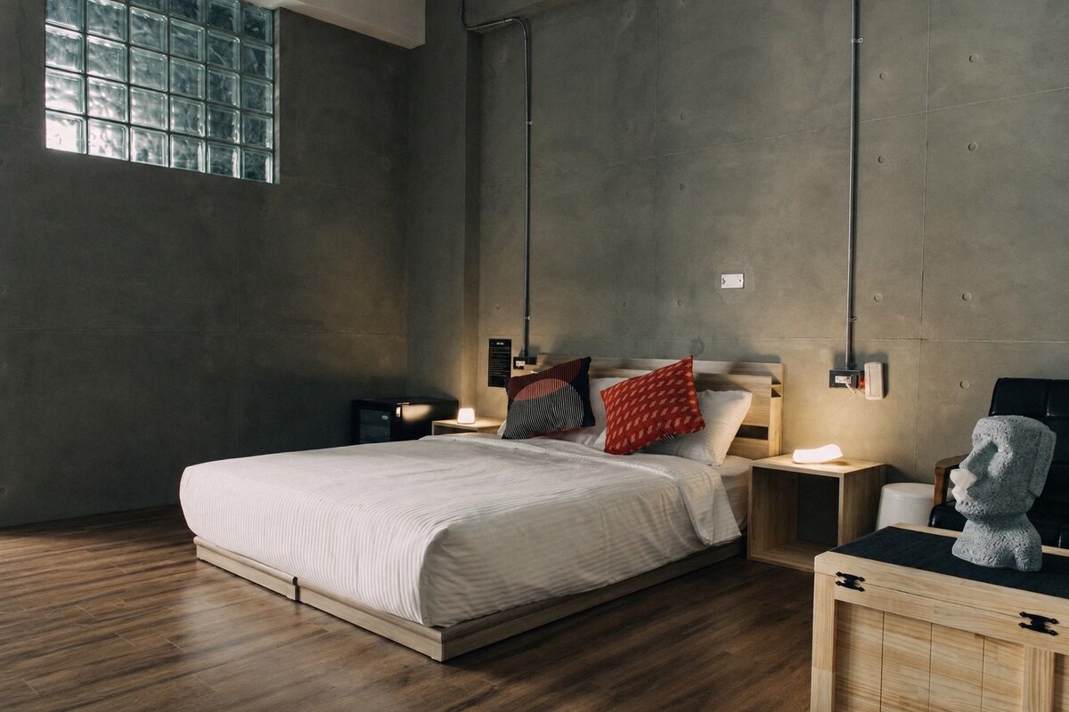 Ein modernes Schlafzimmer mit einem großen Bett, Holzböden und Blick durch ein Fenster.